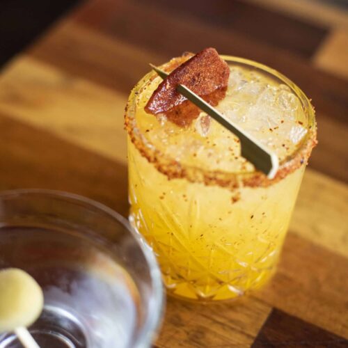 Tequila, champagne, mango, lime, and a chili mango garnish