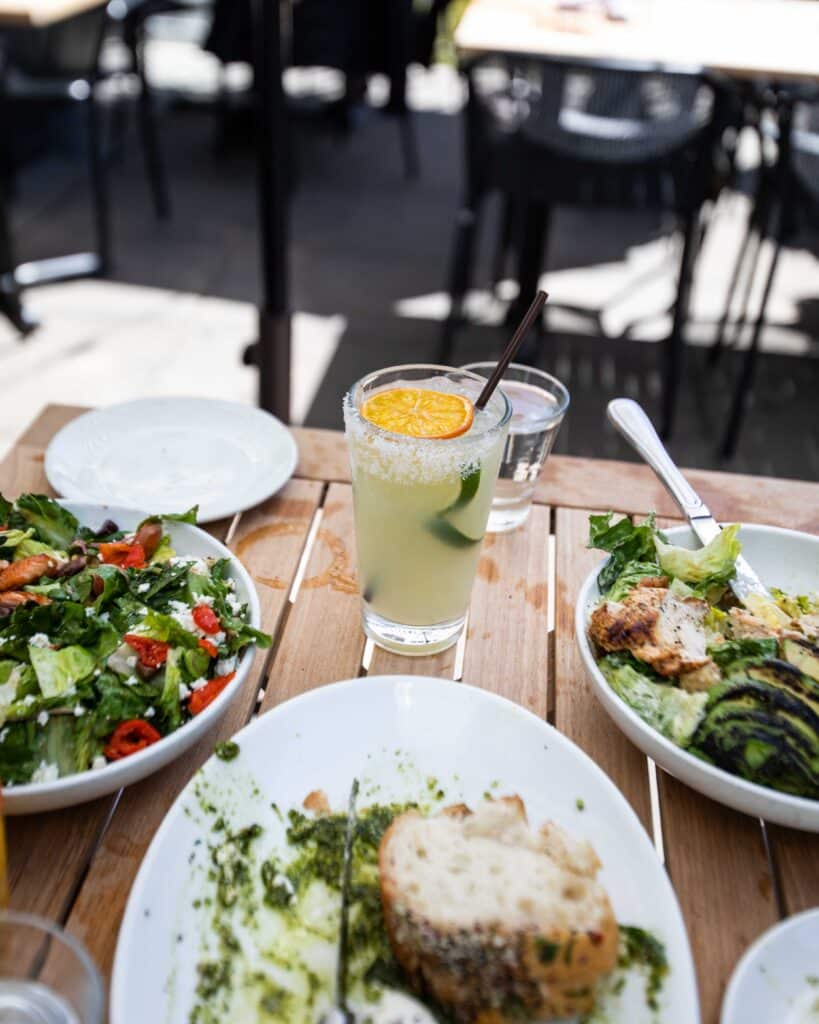 Image of a table with food and drinks on a sunny outdoor patio at Von's 1000Spirits in Downtown Seattle. There is a Margarita on the rocks looking particularly delightful in the photo. 